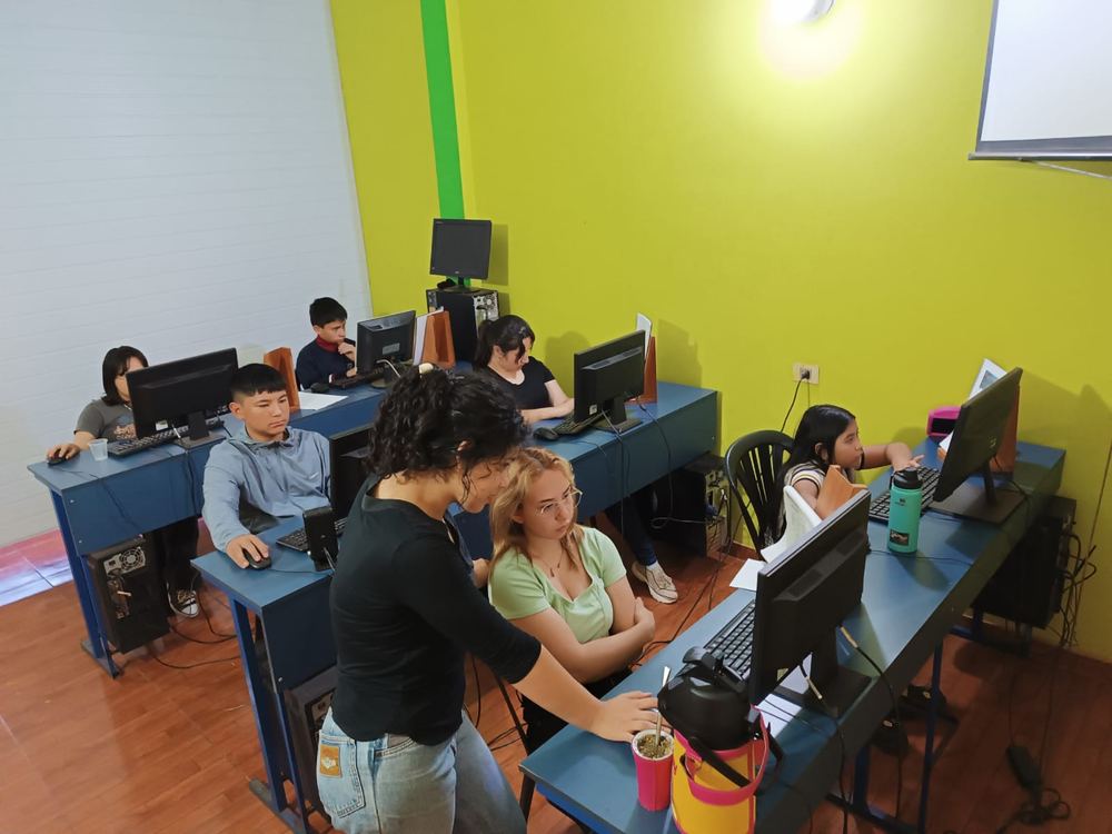La profesora explicando a una alumna mientras el resto del grupo practica.