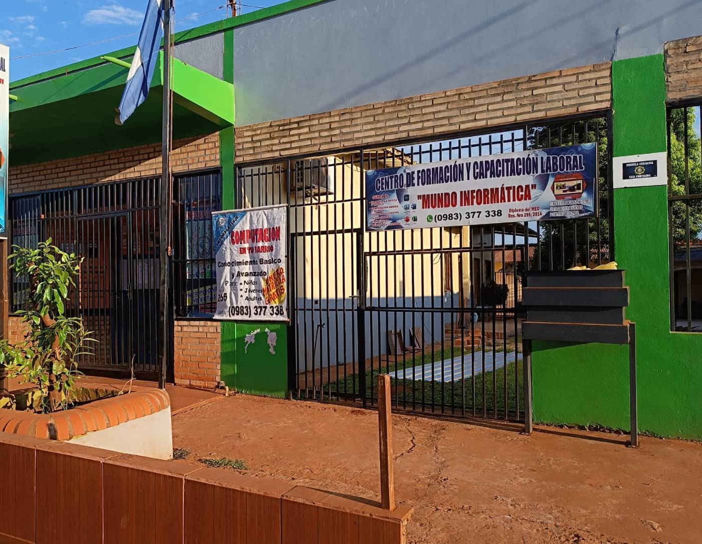 La fachada del instituto Mundo Informática, con sus carteles y la bandera paraguaya.